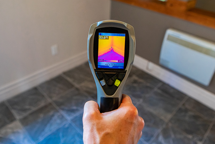 Person using a thermal imaging device while preforming home inspection services 